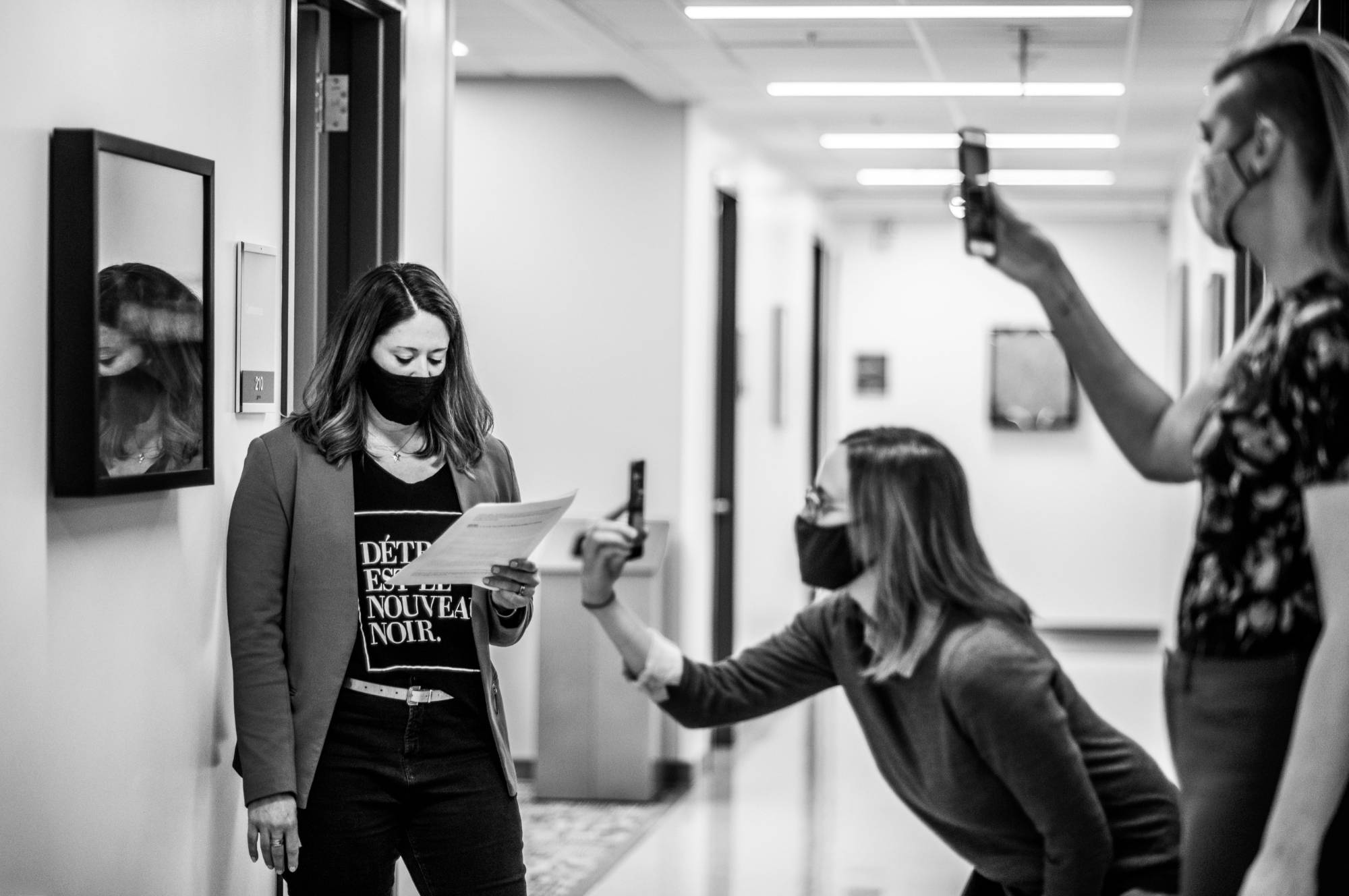 Two students take photos of another student using their phones